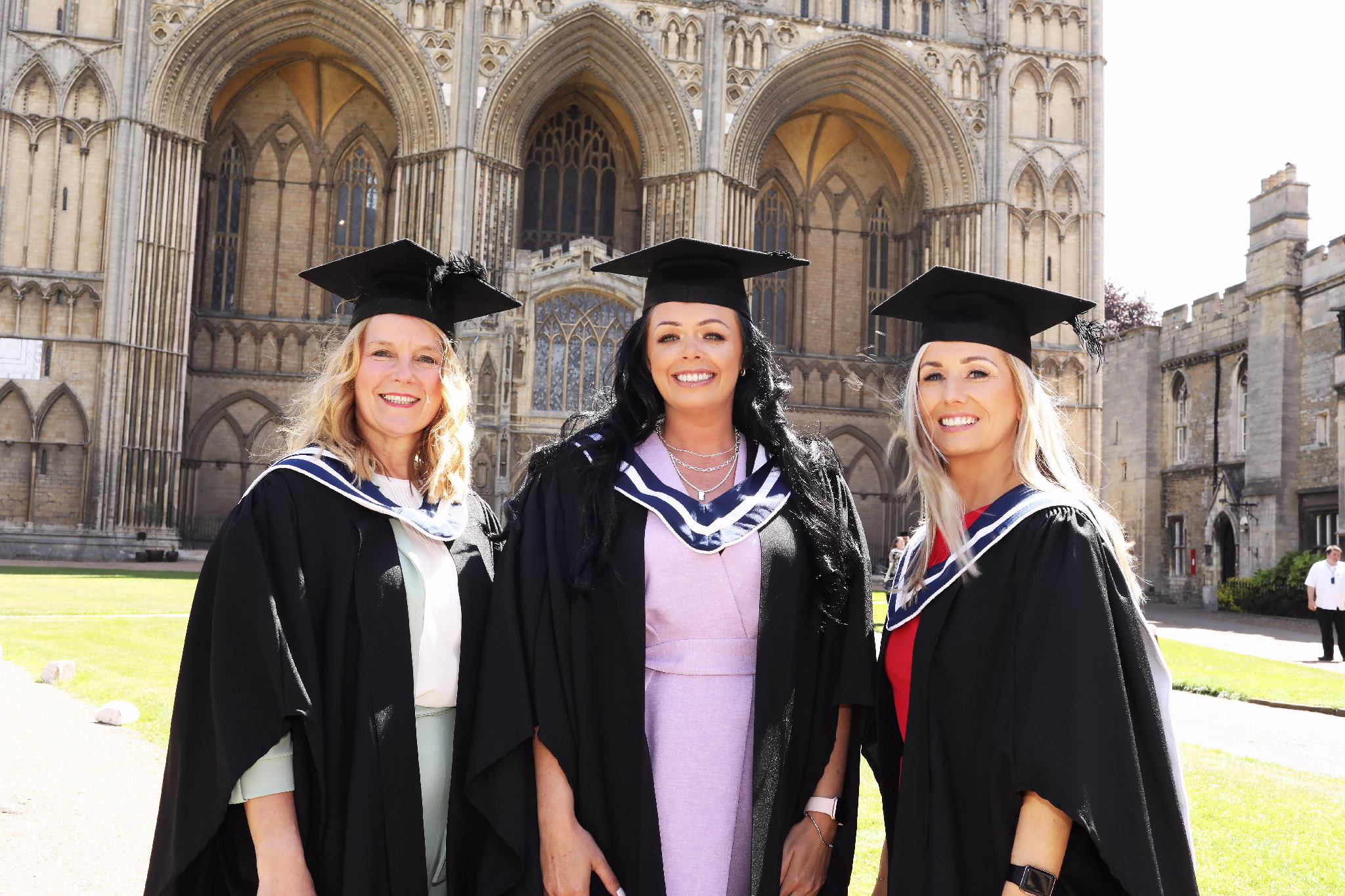 Three female graduates posing outdoors in front of the cathedral