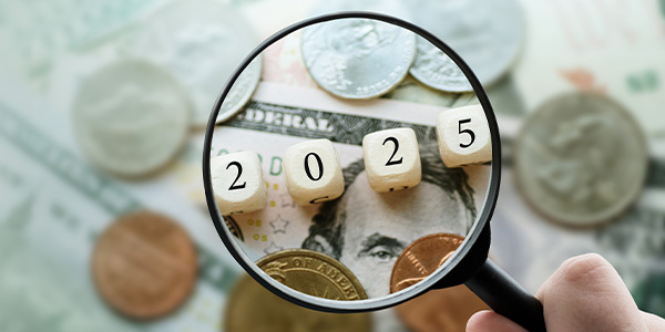 Magnifying glass showing 2025 dice on top of paper money and coins