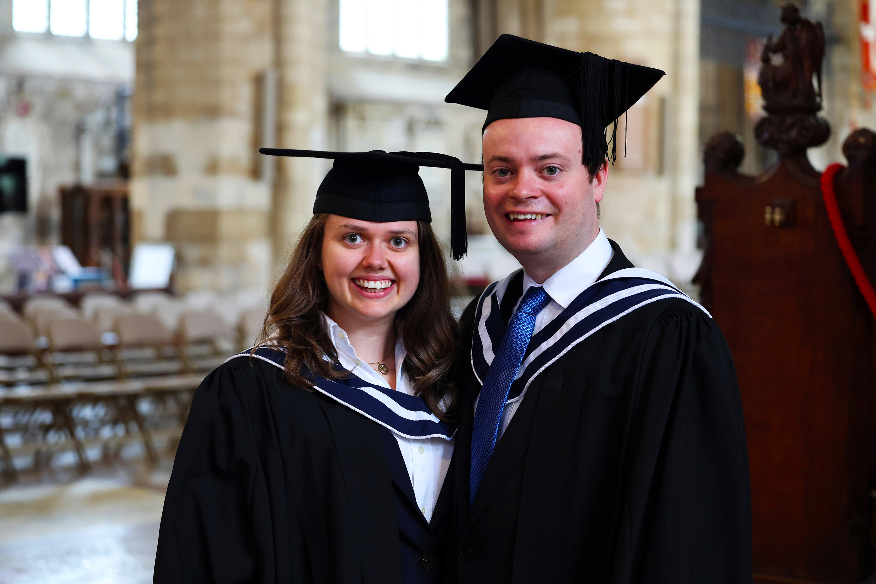 Two graduates posing and smiling together inside the venue