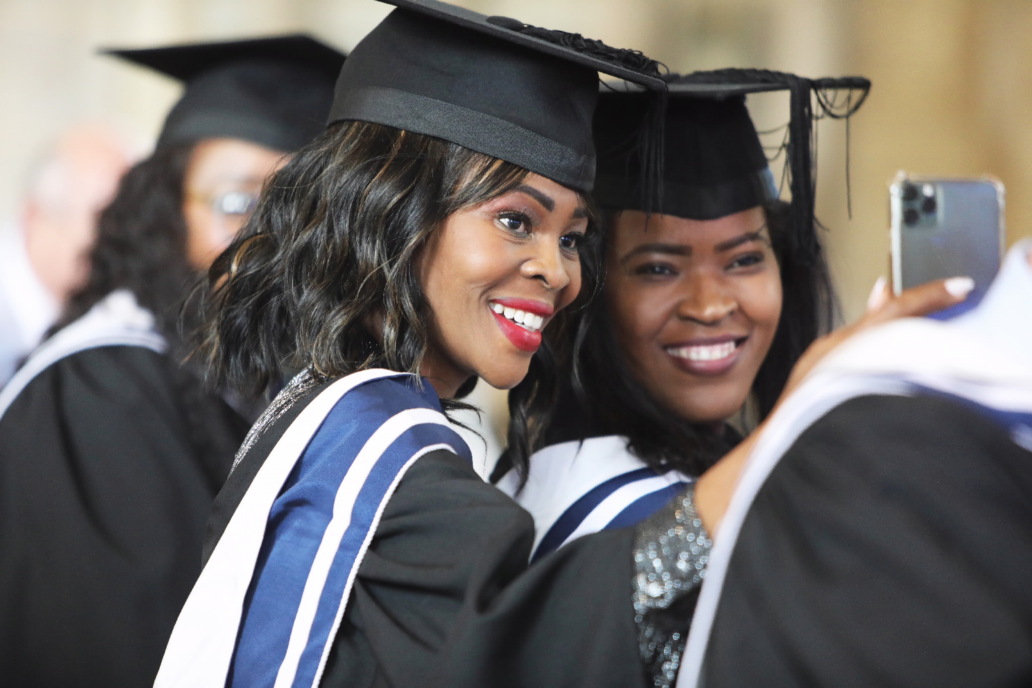 Two graduates smiling while taking a selfie at the event
