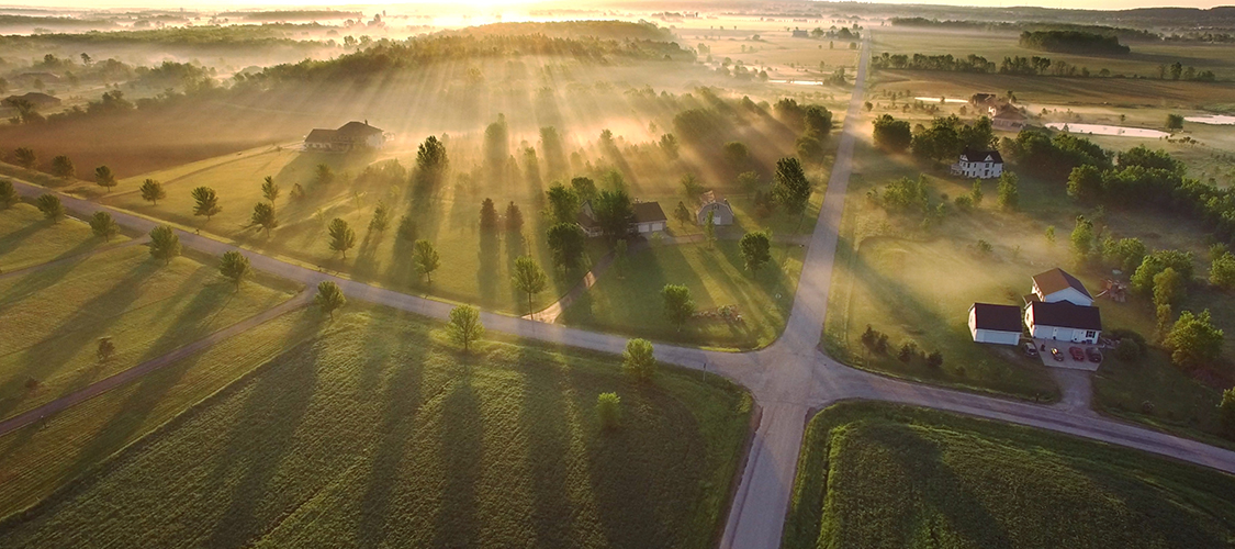 A beautiful sunrise over rural homes surrounded by trees