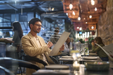 Man in a beige suit wears HOYA VisuPro glasses for reading a restaurant menu