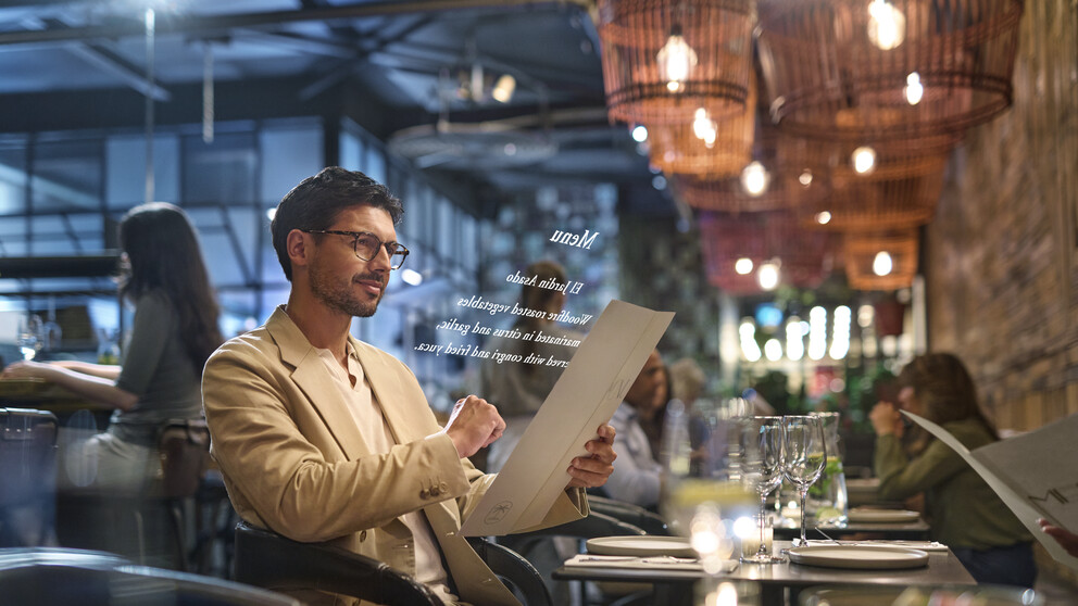 Pria berjas krem ​​memakai kacamata HOYA VisuPro saat membaca menu restoran