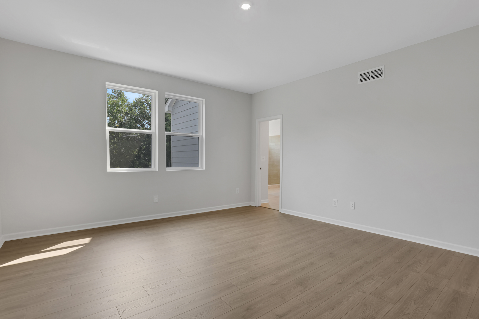 primary bedroom with windows and hard surface floors