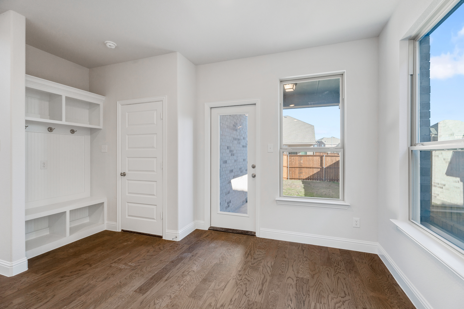breakfast area and mud room with wood flooring, large windows, valet bench with hooks, and a glass door