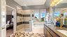 primary bathroom with tile flooring, double sink vanity, a glass walk-in shower, and a soaking tub