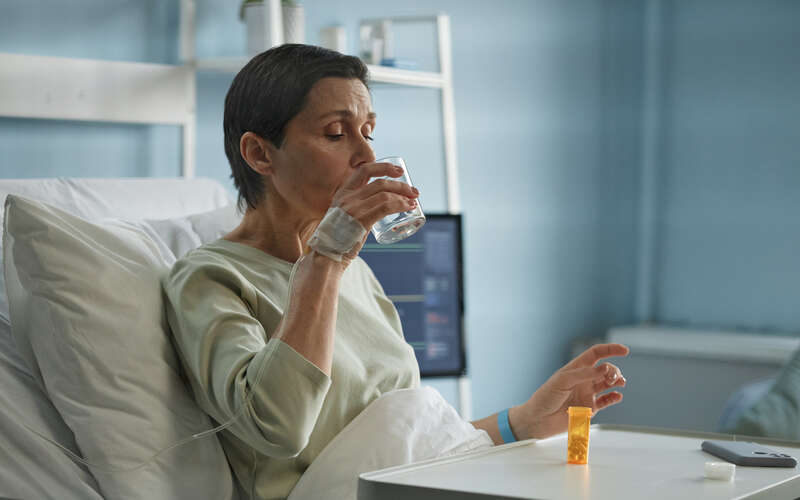 image of woman in hospital bed taking a pill