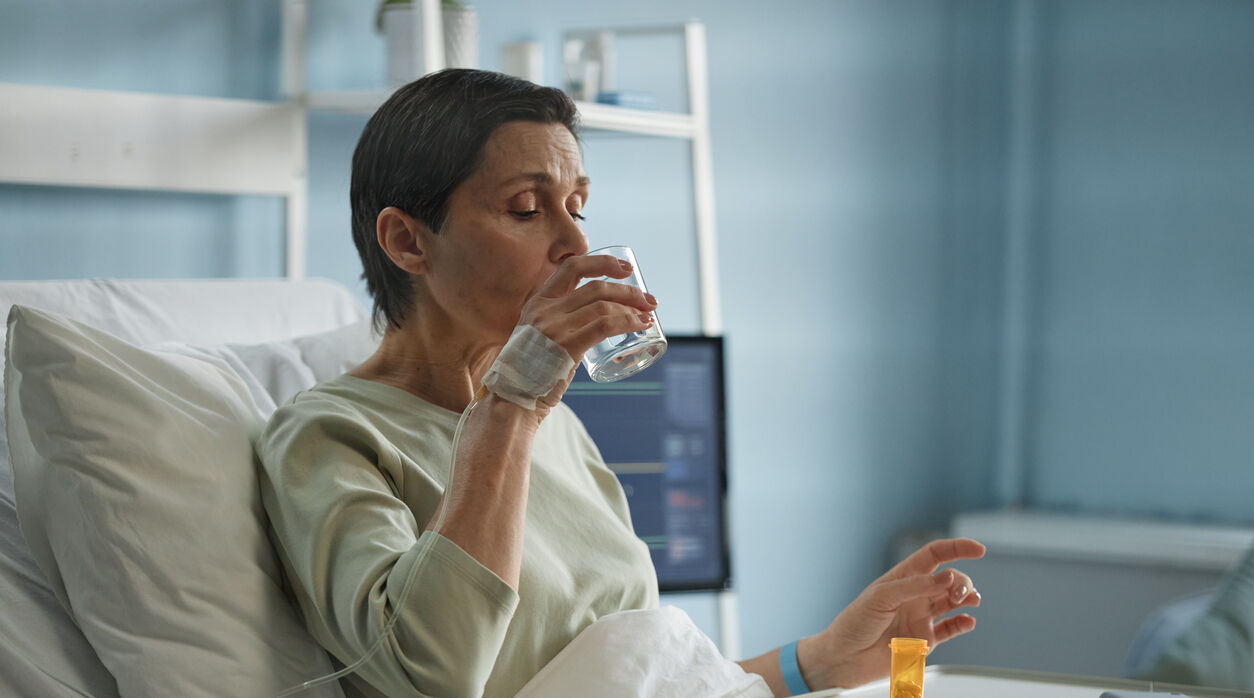 image of woman in hospital bed taking a pill