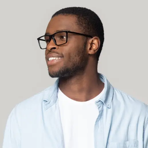 A headshot of a smiling man with black-rimmed glasses and a light blue denim shirt, looking slightly off to the side.