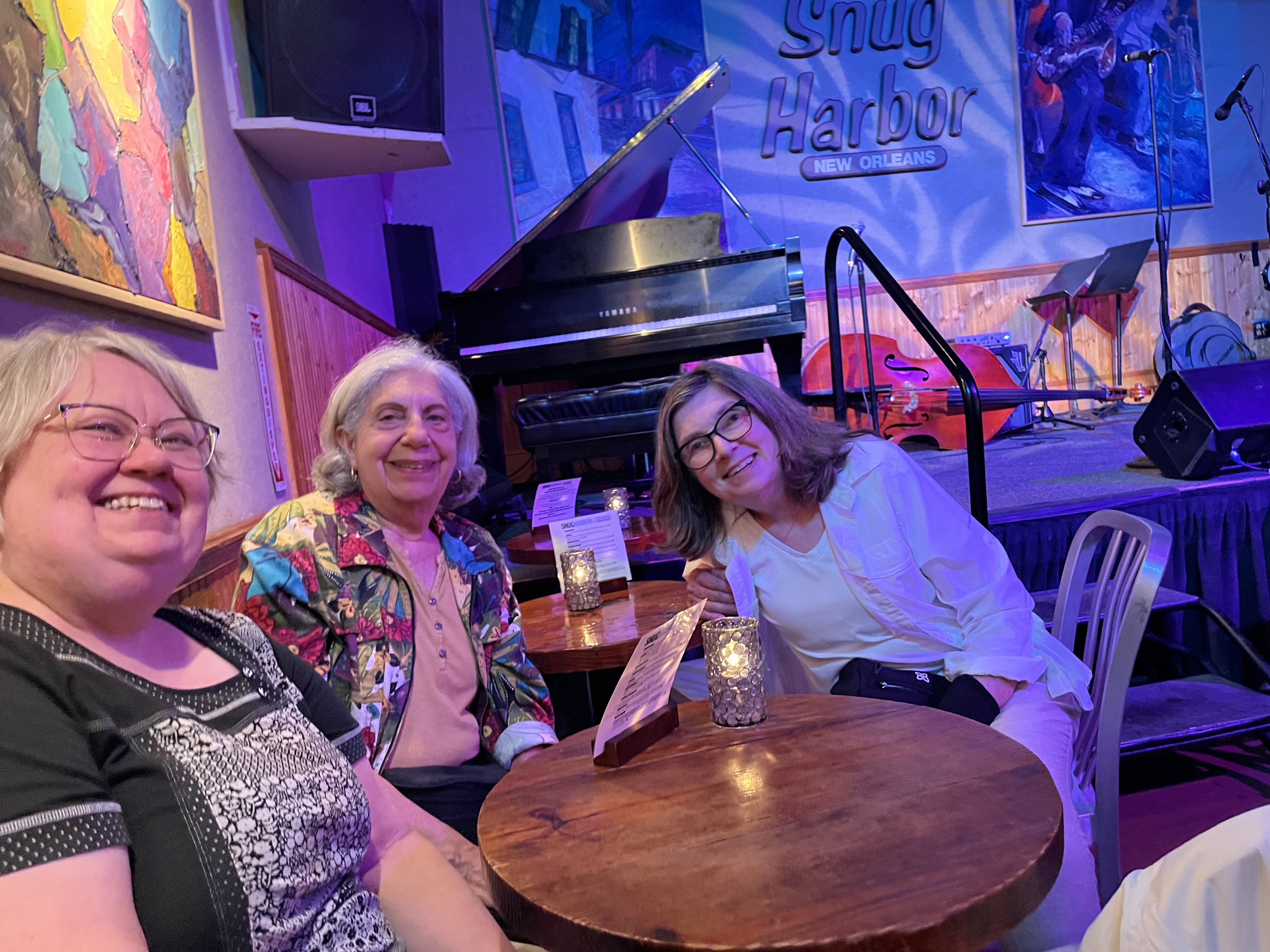Barbara and friends smile together in front of the stage at Snug Harbor