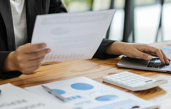 Woman sitting at a desk working on a laptop and looking at documents