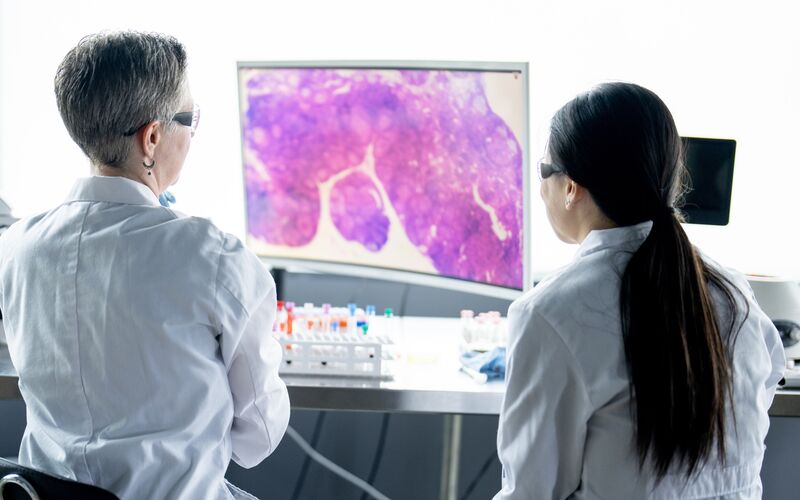 Two female clinicians looking a specimen on a computer screen