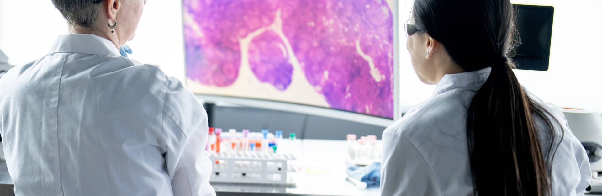 Two female clinicians looking a specimen on a computer screen