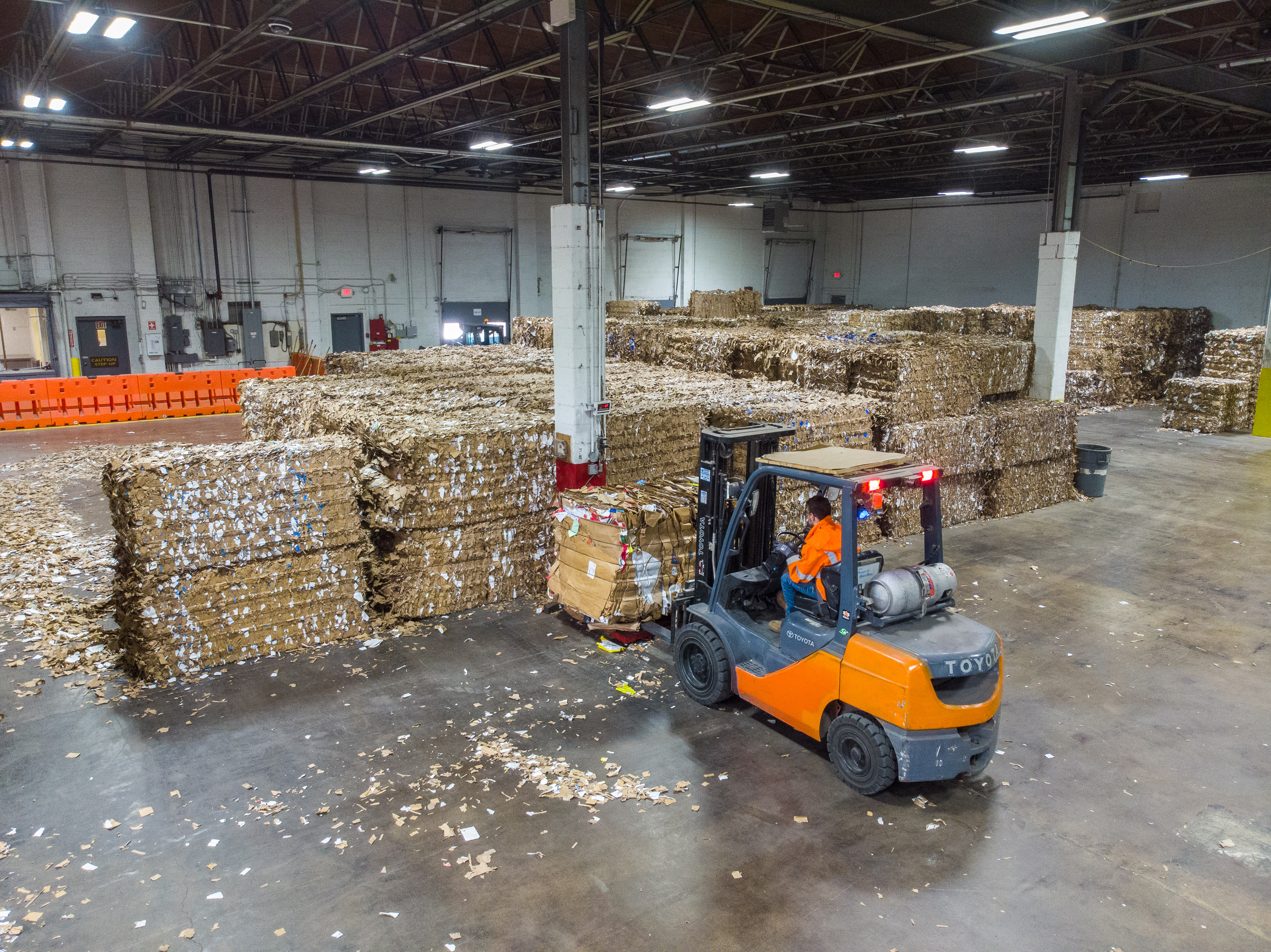 A forklift lifting bales of cardboard
