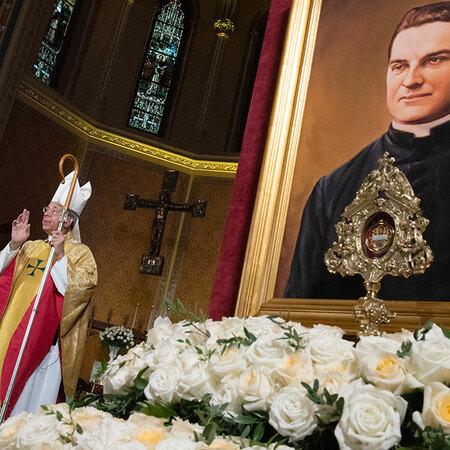 Archbishop Lori holds a staff and prays infront of a portrait of Michael McGivney at St. Mary's in New Haven, Connecticut.