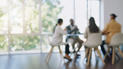 Blurred image of four people sitting at conference table