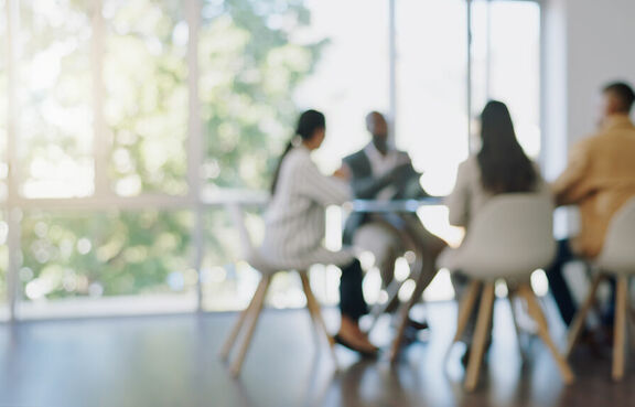 Blurred image of four people sitting at conference table