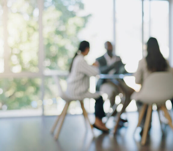 Blurred image of four people sitting at conference table