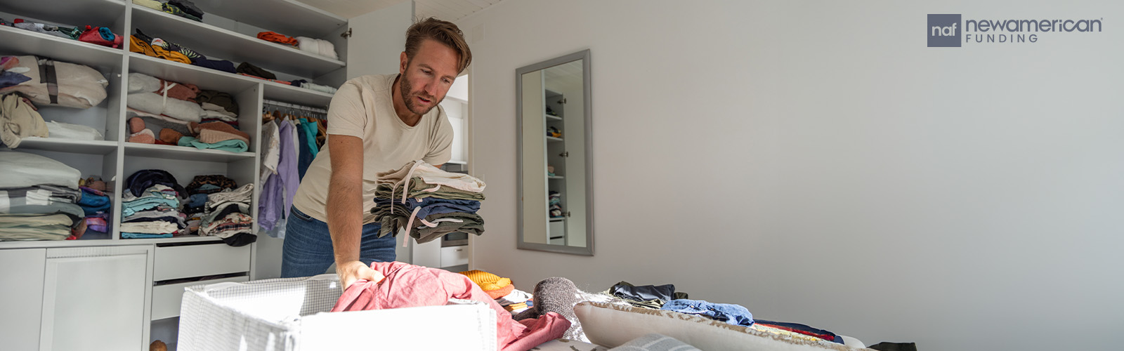 A man cleans out his closet, stacking clothes in a box