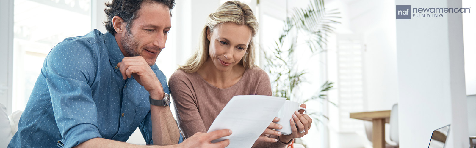 A white couple looks at paperwork together in their home