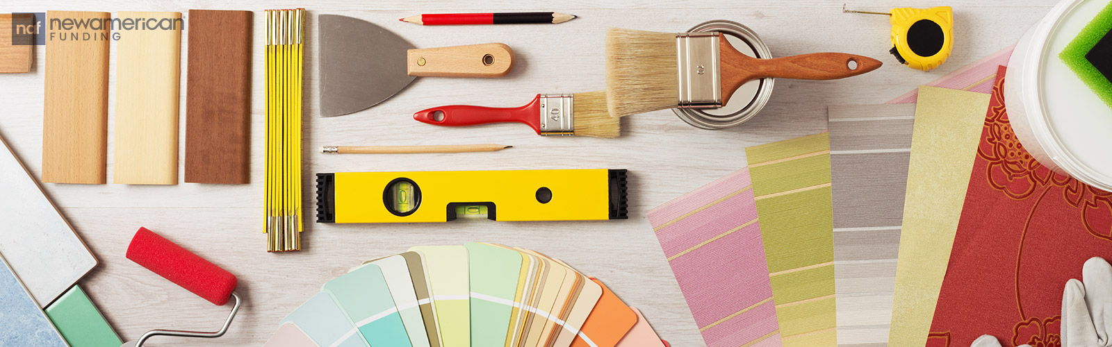 Various DIY supplies sit on a table including paint swatches, paint brushes, and a roller 
