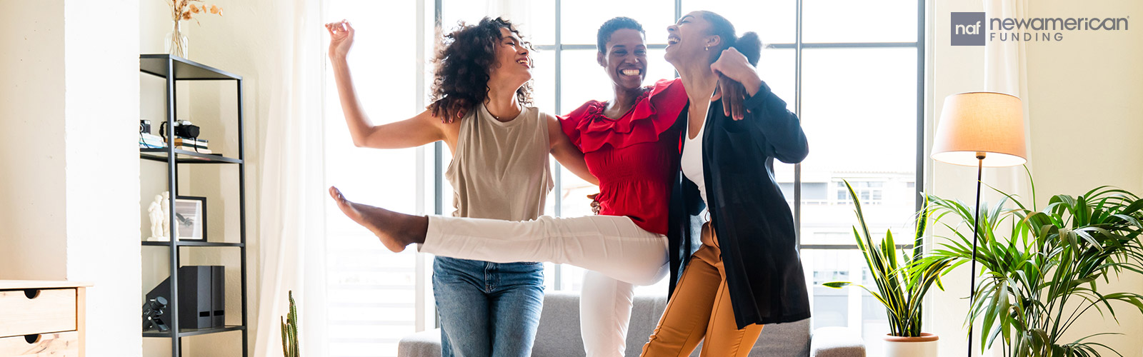 Three Black women all laughing and dancing in their living room