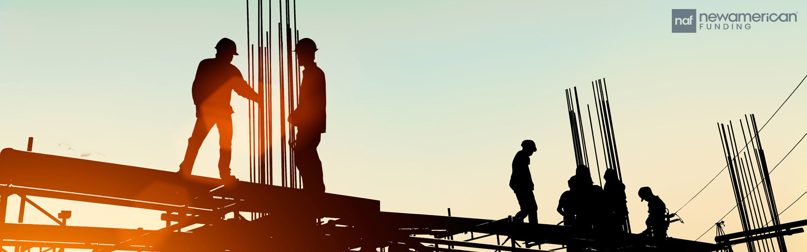 Silhouettes of construction workers standing on the beams of a building under construction