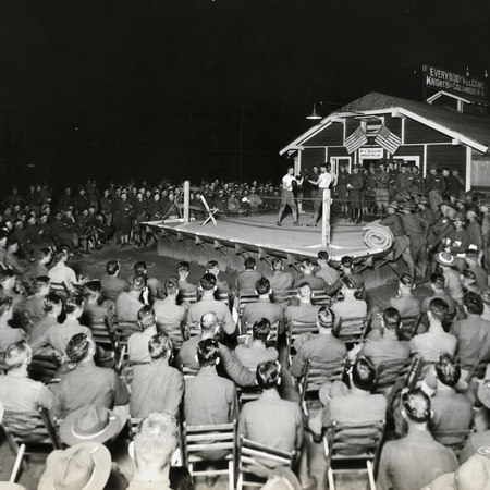 Military members watch a boxing match in a Knights hut.