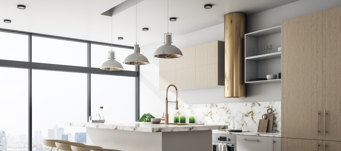 The interior luxury kitchen of a condo with light wood and a kitchen island and the view of skyscrapers out the window.