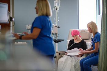 Nurse reviews paperwork with a woman receiving an infusion