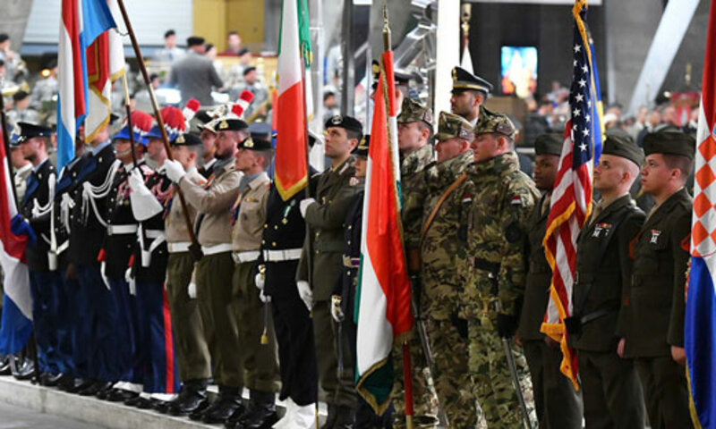 Military members from different countries visit the site of St.Bernadette's apparitions holding their countries flags abnd pray for peace.