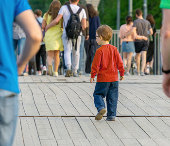 Izgubljen otrok v množici - deček v rdeči majici sam hodi med množico odraslih