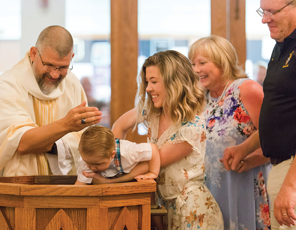 Faith holds Noah as he is baptized by Father David Veit
