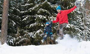 Oče z otrokom uživa na snegu, po tem, ko sta prej uživala v zimskih športih.