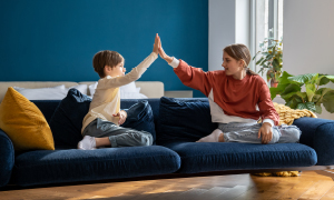 Otroka - sorojenca - sedita na kavču in si dajeta petko