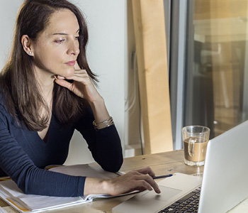 Ženska na sliki pregleduje svojo e-pošto in skuša prepoznati phishing sporočila.