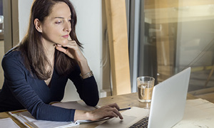 Ženska na sliki pregleduje svojo e-pošto in skuša prepoznati phishing sporočila.