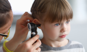 Zdravnica išče znake vnetja ušesa pri otroku