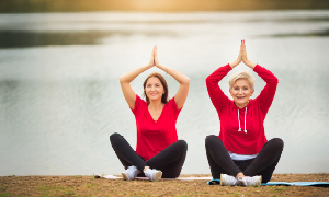 Ženski po 50-tem se na nabrežju jezera ukvarjata z jogo.