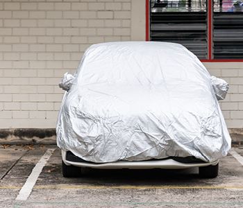 Avto - pripravljen na daljše mirovanje, je voznik prekril s pregrinjalom in parkiral pod streho.