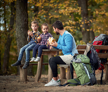 Kam na izlet z otrokom - oče se je na izletu z dvema majhnima otrokoma ustavil, da so skupaj pojedli malico.