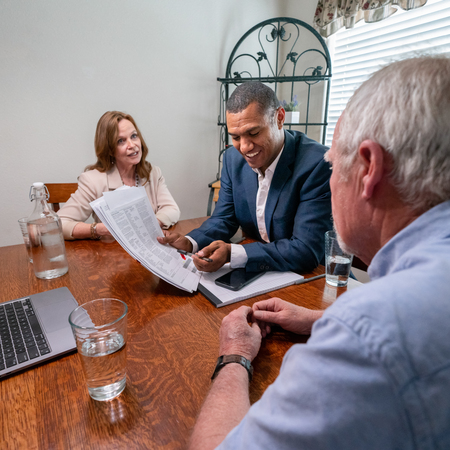 Senior couple sitting at a table with an agent, discussing work together.