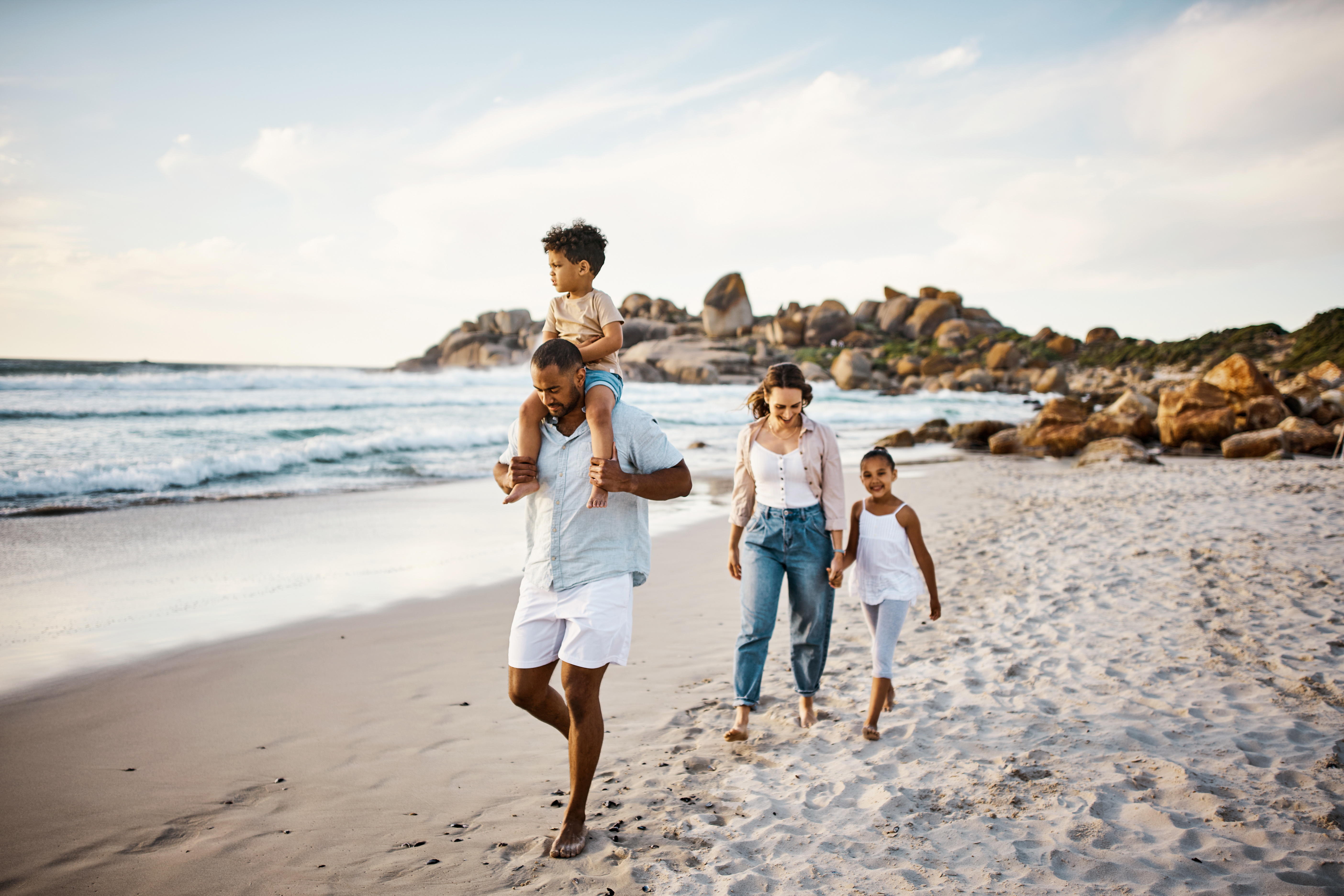 A family strolling on the beach, accompanied by their children, enjoying a leisurely walk by the shore.