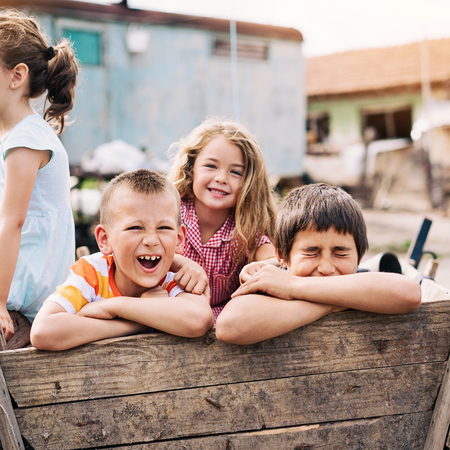 Four children happily sitting in a wooden wagon, enjoying a fun-filled ride together.