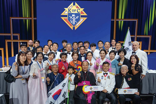 Delegates from the Republic of Korea take a photo together after the States Dinner on Aug. 6, making a gesture, popular in Korea, called the finger heart. Seated in the front row (left to right) are Bishop Titus Seo Sang-bum of the Military Ordinariate of Korea; Maj. Gen Shin Kyoung-soo, the jurisdiction’s territorial deputy; and retired Marine Col. Charles Gallina, who has worked closely with the Knights in Korea for many years. (Photo by Tamino Petelinšek)