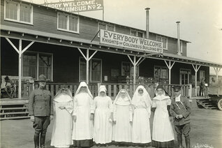 Knights of Columbus secretary Thomas Clines (left) and military chaplain Father Regis Barrett (right) stand with religious sisters who volunteered as nurses at Camp Zachary Taylor, Ky. During the 1918 influenza epidemic, the K of C hut was used as an emergency hospital.