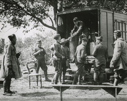 1918 Black and white photo of a Knight passing a cup to a U.S. soldier from a rolling kitchen