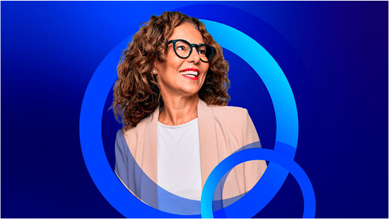 A smiling woman with curly hair and glasses, wearing a light pink blazer over a white top, looks up and to the right. The background is a bright blue with concentric blue circles.