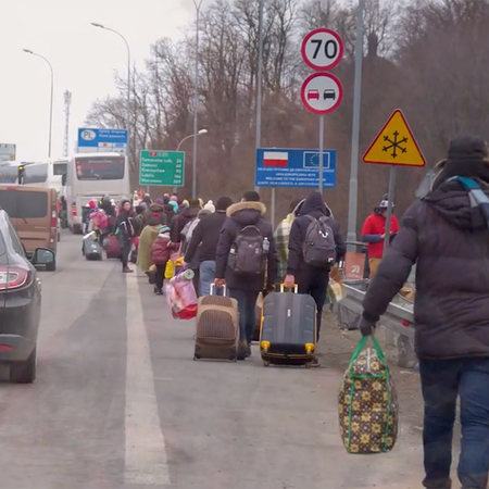 A long line of Ukrainian refugees line the streets with luggage to board rescue buses.