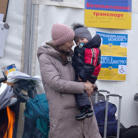 A mother and her young baby snuggle in outerwear at a refugee camp in Ukraine.